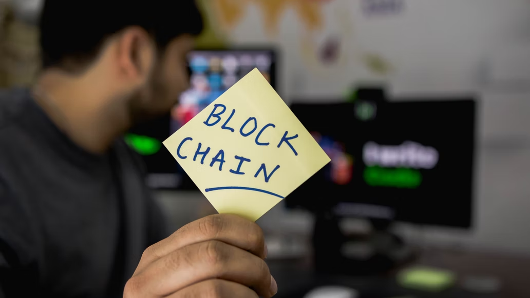 Person showing blockchain written on a paper 