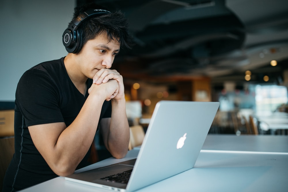 An accountant wearing headphones following an online course on accounting on their laptop